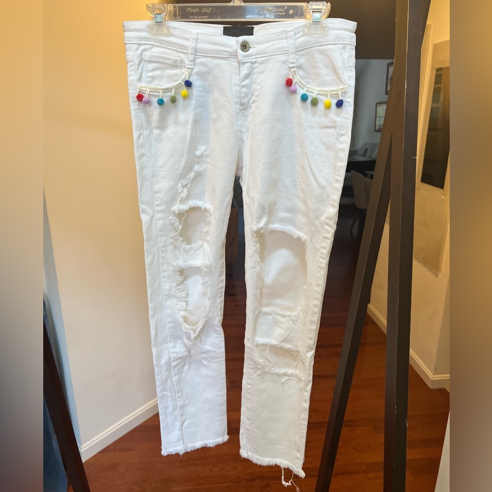White ripped jeans with colorful hanging poofs on pockets